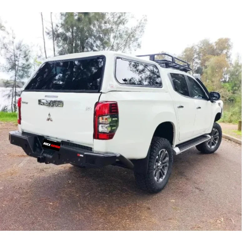 White Mitsubishi pickup truck rear fitted with rockarmor elite rear steel checker plate step and high lift jack mount
