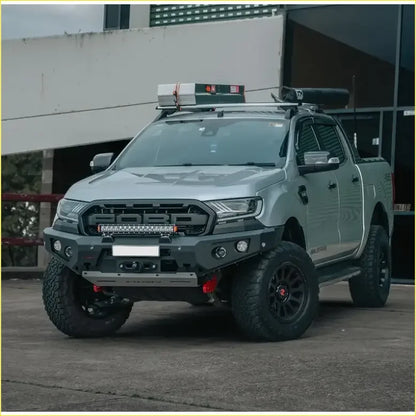Silver ford ranger with black off-road tires and rugged front bumper featuring rockarmor gt hoopless bullbar and sliders